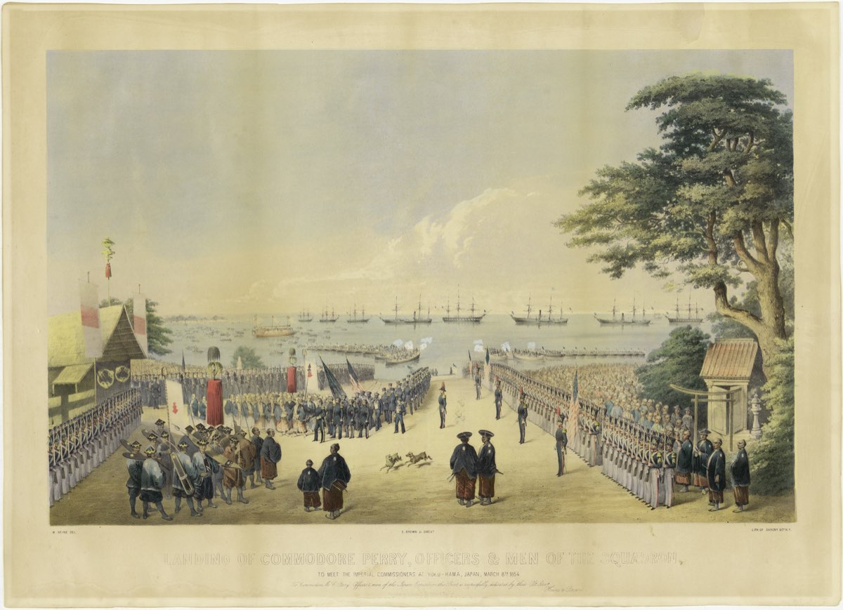 Hand-coloured lithograph of a wide shore scene; American sailors and marines march in columns between long rows of uniformed men toward a large wooden hall hung with banners on the left, while officials in wide hats watch in the foreground, a large tree and a small shrine gate stand on the right, and sailing warships and small boats fill the bay behind